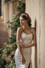 Bride in a wedding dress is standing by the window, romantic atmosphere of the bride's morning