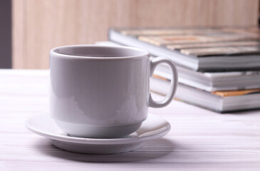 a white ceramic cup with black tea and diffrent objects on the light background