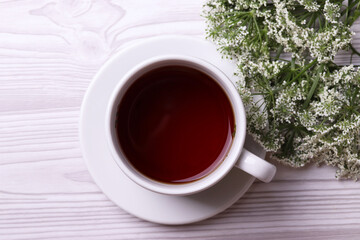 a white ceramic cup with black tea and diffrent objects on the light background