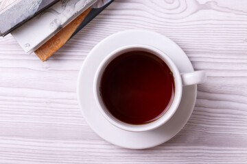 a white ceramic cup with black tea and diffrent objects on the light background