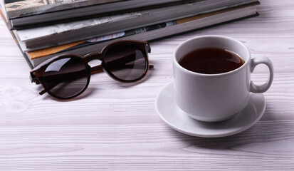 a white ceramic cup with black tea and diffrent objects on the light background