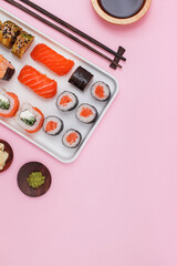 Sushi set with salmon on pink background, top view.