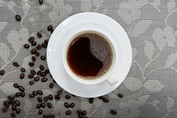 Black coffee in a white cup and coffee beans on the table top view