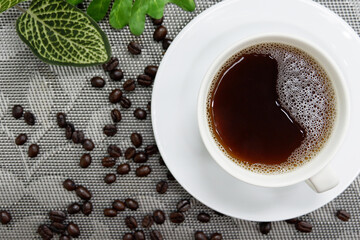 Black coffee in a white cup and coffee beans on the table top view