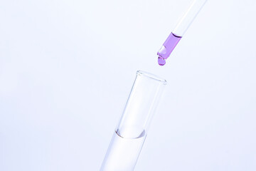 drop of liquid falls into a test tube on a gray background