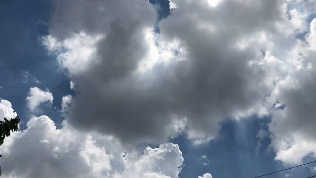 Beautiful dark rain storm clouds and white fluffy on sky,thunderstorm in dramatic sky,with lens flare.Climate cloudscape,selective focus.Weather tropical  summer squall.Time lapse footage. 