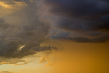 Fototapeta na wymiar Grey clouds in a diffuse orange sunset sky