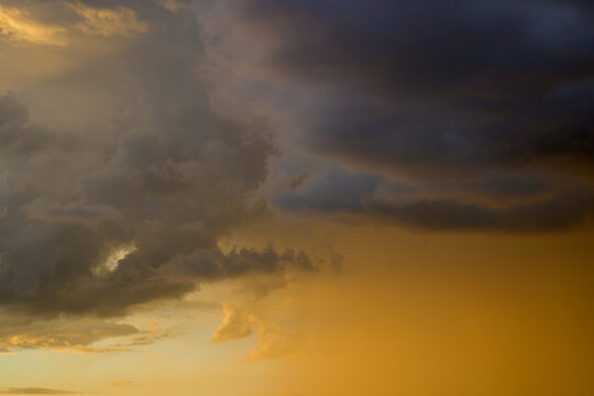 Grey clouds in a diffuse orange sunset sky
