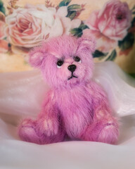 Cute pink teddy bear sitting in front of painted roses