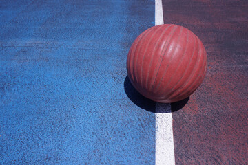 Close-up of basketball ball on old cement court floor in the outdoor. The colorful court, Red and...