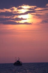 Ship sailing in the ocean  with sunset and rays of the sun.