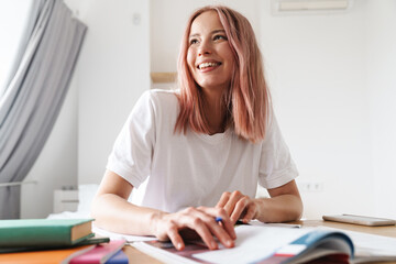 Image of smiling caucasian woman doing homework with exercise books