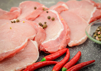 Raw pork steaks on a marble board with spices