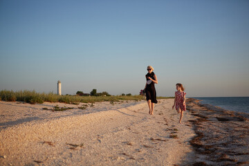 Smiling mother and beautiful daughter having fun on the beach. Portrait of happy woman giving a...