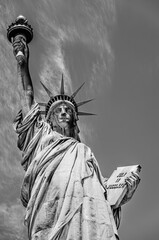 Close up of the Statue of Liberty designed by Alexandre Gustave Eiffel on a clear blue sky background with 4th of July writing visible on Liberty Island, New York, USA in black and white © PhotoFires