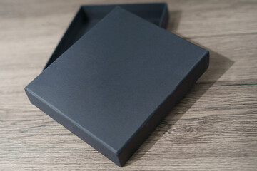 Opened black cardboard box on a brown wooden table.