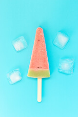 Ice cream with watermelon flavor and ice cubes on blue background, a copy of the space