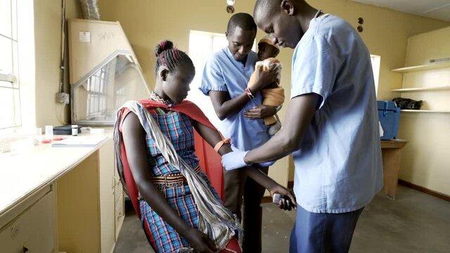 Doctors working with mothers and babies in busy neonatal clinic. Africa