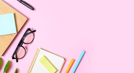 Pink background with notepad, office glasses, pen, place for text. Trend concept.