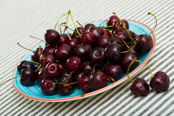 Image of fresh tasty red cherries on blue plate
