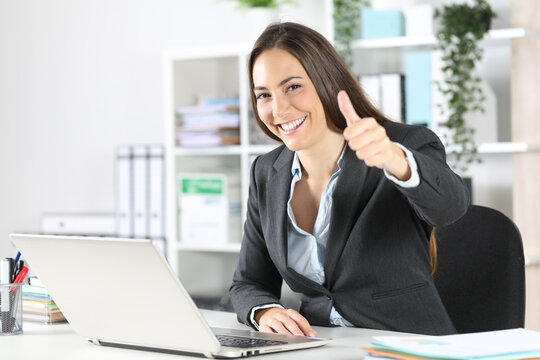 Happy executive with thumbs up looking camera at office