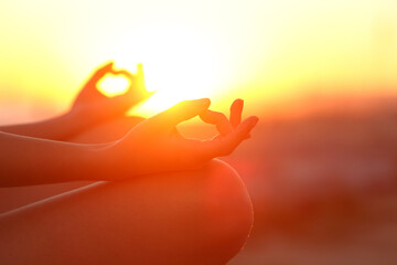 Woman hands doing yoga relaxing at sunset outdoor