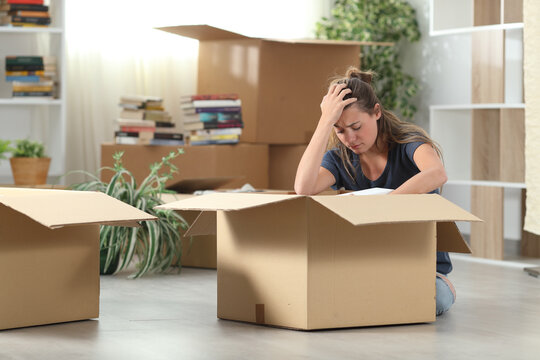 Sad evicted woman moving out packing boxes at home