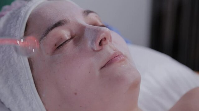 Receiving electric darsonval facial massage procedure.