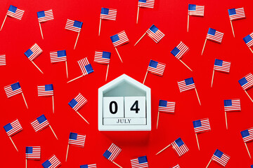 July 4th. Mockup of july 4 wooden color calendar and USA flags on red background. Independence Day...
