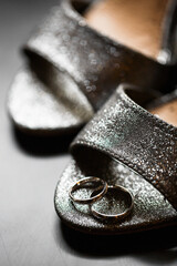 On the bride's shoes. Wedding rings on a shiny surface.