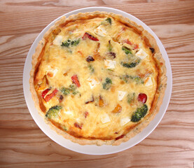 Pie with cheese and vegetables - top view on a wooden table.