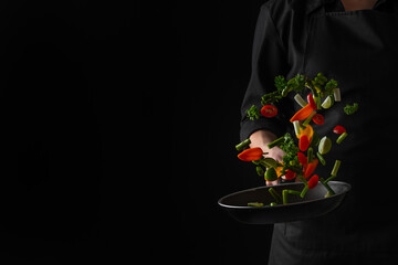 Professional chef fry vegetables in a pan, freeze in motion, on a black background, banner, veggie food, tasty and wholesome food
