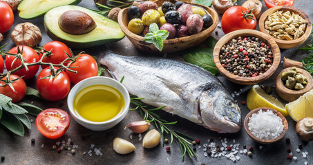 Raw dorado fish with spices and vegetables on the graphite board.