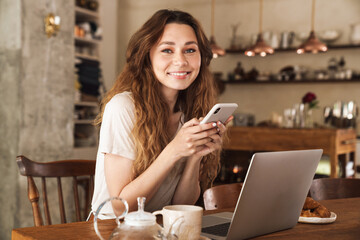 Beautiful young smiling girl sitting at the kitchen table