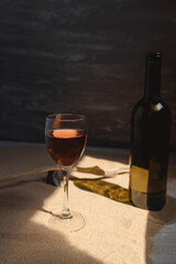 Glass of red wine in arched sunlight on the sand.