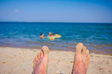 Man's legs on the beach, relaxing by the sandy beach