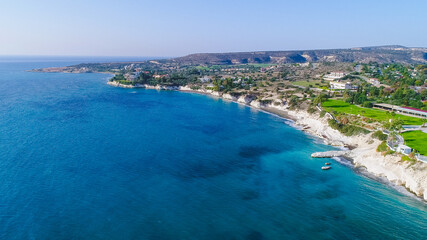 Fototapeta premium Aerial view of coastline and landmark big white chalk rock at Governor's beach,Limassol, Cyprus. Steep stone cliffs and deep blue sea waves next to Kalymnos fish restaurant and vasilikos power station