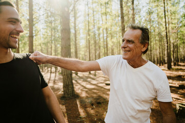 Young caucasian happy spending time with adult son in the woods on a run