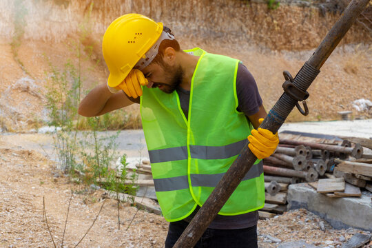 Tired Construction Worker Wiping Forehead At Site