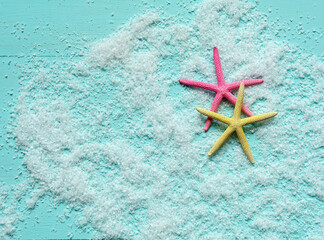 Fototapeta na wymiar Two beautiful colored starfish lie on artificial sea foam on turquoise wooden background. Place for text. Banner template.