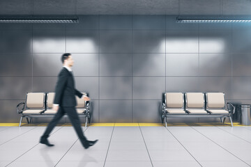 Businessman walking in modern underground railway station.