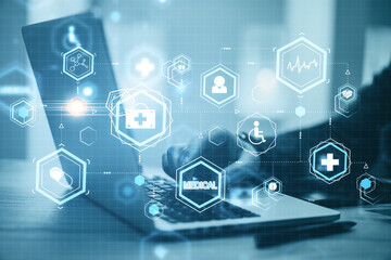 Hand using laptop with creative glowing blue medical hologram.