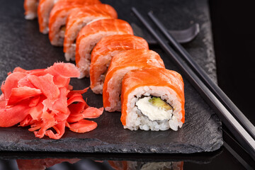 Beautiful Philadelphia rolls with salmon and cream cheese on a plate of black slate.