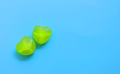            two heart-shaped green lollipops on a blue background,   space for text,  love concept  ...