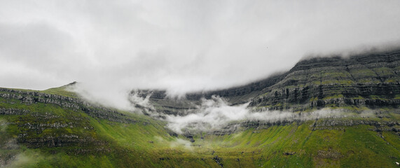 Faroe Islands aerial landscape photography with outstanding green mountains with thick clouds. 