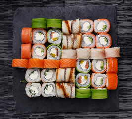 Japanese sushi set. Various types of roles on plate over stone background. Top view.