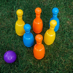 Children's set to play bowling on green grass. Ball and colored pins. Kid's game toy. Bowling colorful plastic pins. Active and interesting childhood concept.