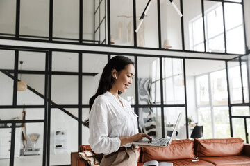 Attractive young brunette asian woman using laptop