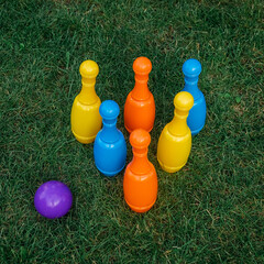 Children's set to play bowling on green grass. Ball and colored pins. Kid's game toy. Bowling colorful plastic pins. Active and interesting childhood concept.
