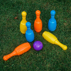 Children's set to play bowling on green grass. Ball and colored pins. Kid's game toy. Bowling colorful plastic pins. Active and interesting childhood concept.